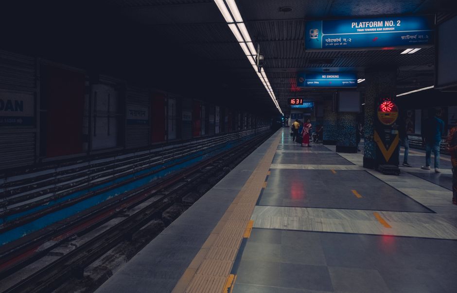 A dimly lit metro station platform with passengers waiting, showcasing urban public transportation.
